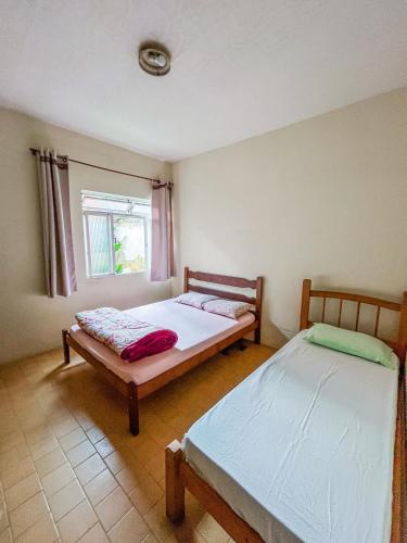 two beds in a room with a window at Ótima casa no centro de Carrancas in Carrancas
