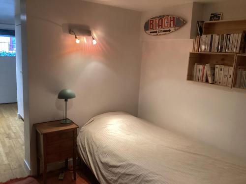 een slaapkamer met een bed en een lamp op een tafel bij Chambres en maison in Fontenay-sous-Bois