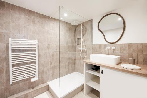 La salle de bains est pourvue d'une douche, d'un lavabo et d'un miroir. dans l'établissement Noble Suites, à Paris