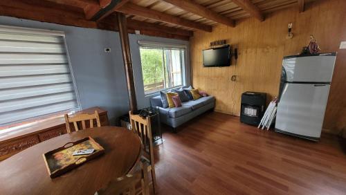 sala de estar con sofá y nevera en Cabaña Pellines, en Coñaripe