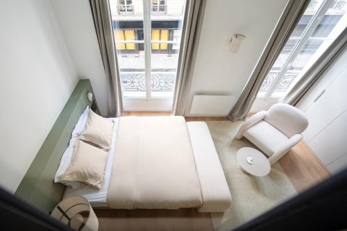 a room with a bed and a chair and a window at Noble Suites in Paris