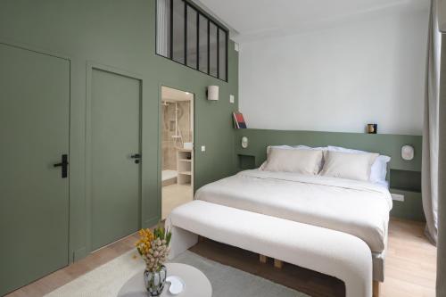 Un dormitorio con una gran cama blanca y una pared verde en Noble Suites en París