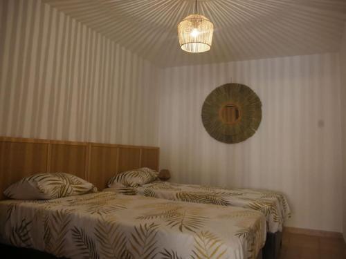 a bedroom with two beds and a chandelier at Luciole des Alpilles in Mouriès