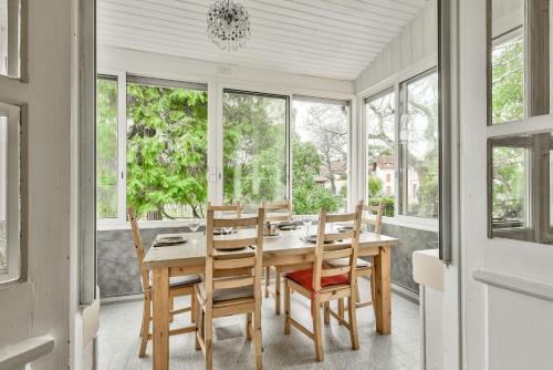 une salle à manger avec une table, des chaises et des fenêtres dans l'établissement Escapade à 150m de la plage du Betey, à Andernos-les-Bains