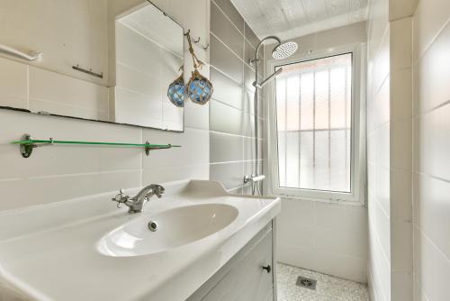 une salle de bain blanche avec un lavabo et une fenêtre dans l'établissement Escapade à 150m de la plage du Betey, à Andernos-les-Bains