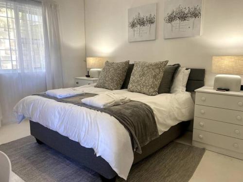 Un dormitorio con una cama grande con sábanas y almohadas blancas. en Couples Cove: Luxe Getaway w/ jetted bath & views, en Ciudad del Cabo