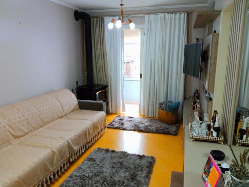 a living room with a couch and a television at Apto aconchegante ao lado da Vinícola Garibaldi in Garibaldi