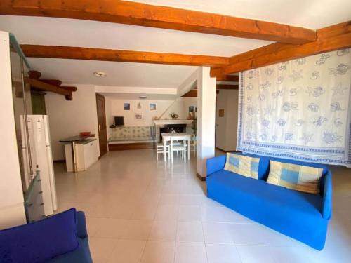 sala de estar con sofá azul y cocina en Capo Coda Cavallo vista mare, en Capo Coda Cavallo