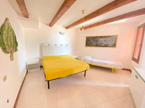 1 dormitorio con 2 camas y manta amarilla en Capo Coda Cavallo vista mare, en Capo Coda Cavallo