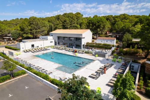 einen Blick über einen Pool mit Stühlen und ein Gebäude in der Unterkunft VVF Montagnac Hérault in Montagnac