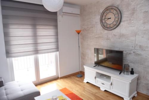 a living room with a television and a clock on the wall at Impressive Apartment in Nikšić