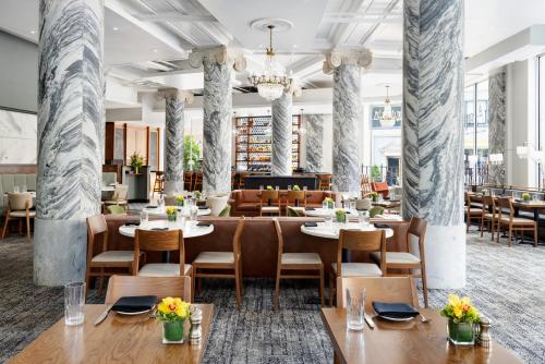 a restaurant with tables and chairs and a chandelier at The Candler Hotel Atlanta, Curio Collection by Hilton in Atlanta