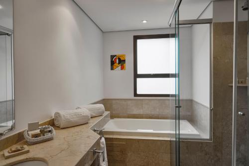 a bathroom with a tub and a glass shower at George V Casa Branca in Sao Paulo