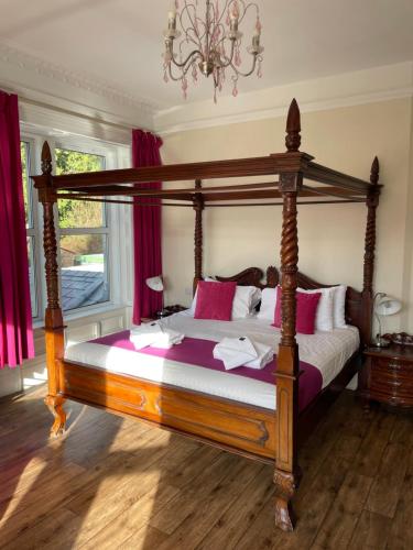 a bedroom with a canopy bed with pink pillows at The Claymore Guest House in Pitlochry