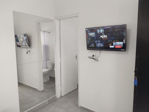 baño con aseo y TV en la pared en Casa Cardoso, en Bertioga