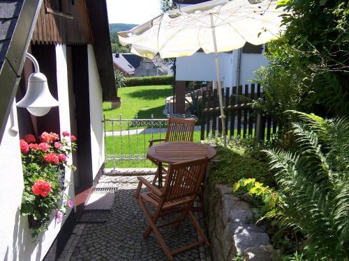 einen Tisch und zwei Stühle und einen Regenschirm auf einer Terrasse in der Unterkunft Ferienhäuschen Grenzland in Bad Elster