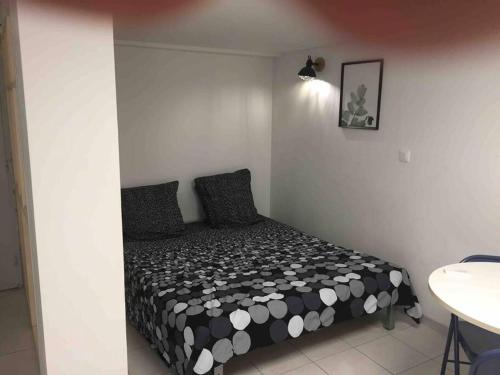 um quarto com uma cama com um edredão preto e branco em Les ruisseaux, studios avec terrasse et jardin em Valence