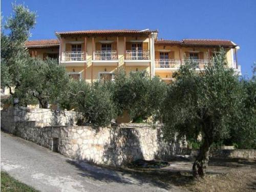 a building with trees in front of a stone wall at Sofos Apartments in Tsilivi