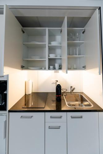a kitchen with white cabinets and a sink at Los Lorentes Apartments Bern Airport in Belp