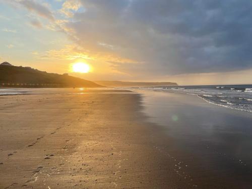 a beach with the sun setting on the horizon at Highgate House in Whitby