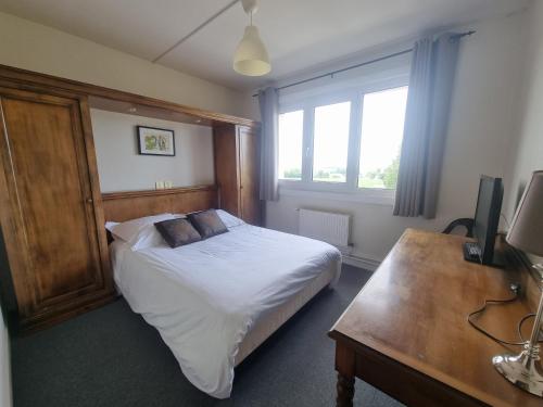 Schlafzimmer mit einem Bett, einem Schreibtisch und einem Fenster in der Unterkunft Hôtel Le Prieuré in Rancourt