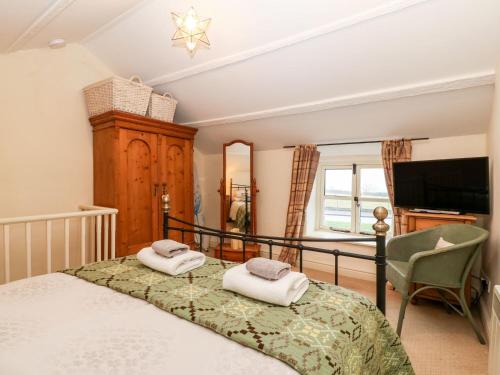 a bedroom with a bed with two towels on it at White Lilac Cottage in Llanfairpwllgwyngyll