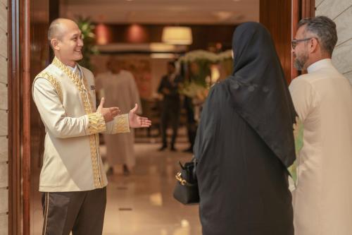 a man and a woman standing next to a priest at Raffles Makkah Palace in Makkah