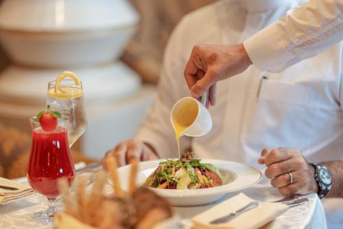 a person pouring a spoon over a plate of food at Raffles Makkah Palace in Makkah