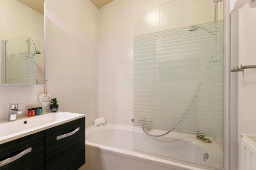 y baño con ducha, bañera y lavamanos. en Modern duplex apartment near the beach en Middelkerke