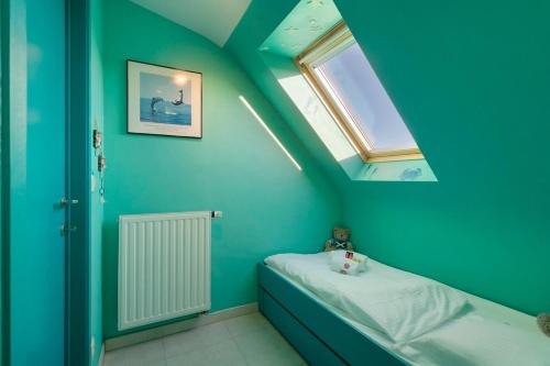 a blue room with a bed and a window at Modern duplex apartment near the beach in Middelkerke