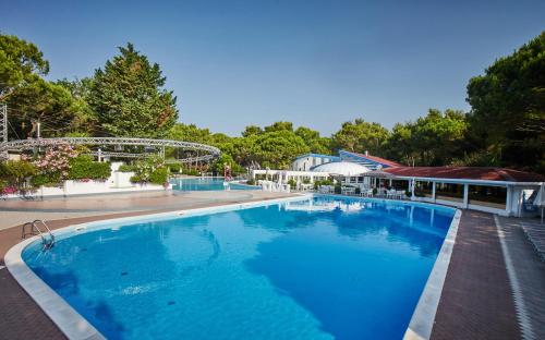 une grande piscine bleue à côté d'un bâtiment dans l'établissement Dei Fiori Camping Village, à Cavallino-Treporti