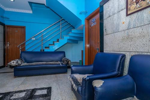 two blue chairs sitting in a hallway with stairs at OYO Royal Inn Near Iskcon Temple Bangalore in Bangalore
