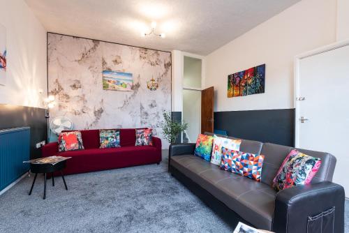 a living room with a red couch and a marble wall at 6 Roomy Bedrooms Favour Spacious Inn - Sleeps 13 Hull Central Location in Hull