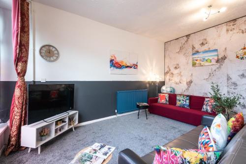 a living room with a red couch and a tv at 6 Roomy Bedrooms Favour Spacious Inn - Sleeps 13 Hull Central Location in Hull