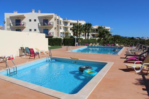 a pool at a resort with chairs and a swimming pool at Buganvília Holidays in Alvor