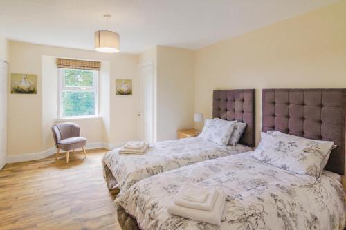 1 dormitorio con 2 camas y 1 silla en Glen Cottage en Cray