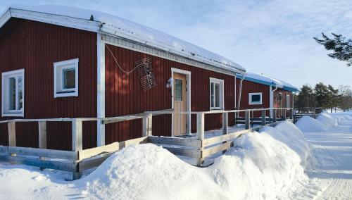 Un bâtiment rouge dans la neige avec de la neige autour de lui dans l'établissement Fritidshus - Cottage - Holiday house - Soluppgång, à Blattniksele