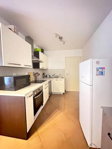 Appartement F3, 2 chambres في إيفري سور سين: مطبخ مع ادوات بيضاء وثلاجة بيضاء