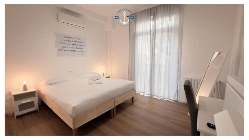 a white bedroom with a bed and a window at La Dolce Sosta Executive in Lido di Ostia