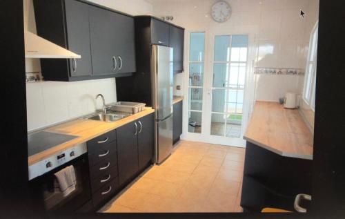 a kitchen with black cabinets and a stainless steel refrigerator at Villa Rochelle in Caleta De Fuste