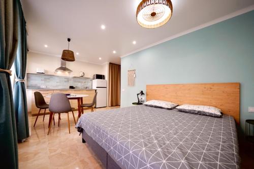 a bedroom with a bed and a table and a kitchen at Parsami Suites in Santa Pola