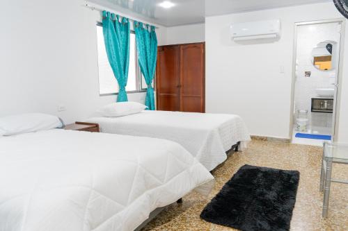 a bedroom with two beds and a blue curtain at HOTEL GANADERO in La Dorada