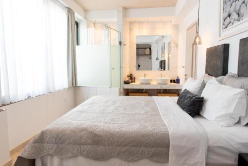 a white bedroom with a large bed and a bathroom at Sea & the City in Thessaloniki