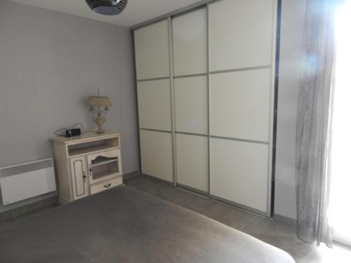 Cette chambre comprend une table et des portes coulissantes blanches. dans l'établissement Appartement à 5mn à pied des plages, à LʼÎle-Rousse