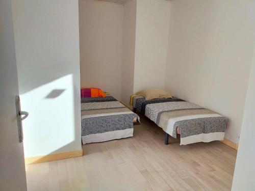 two beds in a small room with wooden floors at Appart 2 chambres proche rivière & centre in Saint-Ambroix