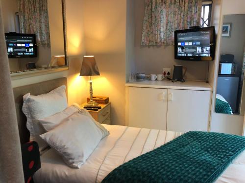 Dormitorio pequeño con cama y TV en Self Catering Guest House, en Ciudad del Cabo