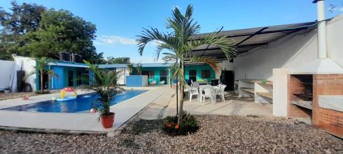 una casa con piscina y palmeras en el patio en CASA QUINTA VILLA CECILIA CARMEN DE APICALA, en Carmen de Apicalá