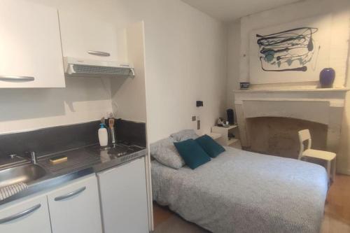 une chambre avec un lit et une cuisine avec une cheminée dans l'établissement Appartements avec balcon au coeur des Chartrons, à Bordeaux