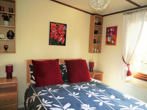 a bedroom with a bed with red pillows at Bend in the River Lodge in Stratford-upon-Avon