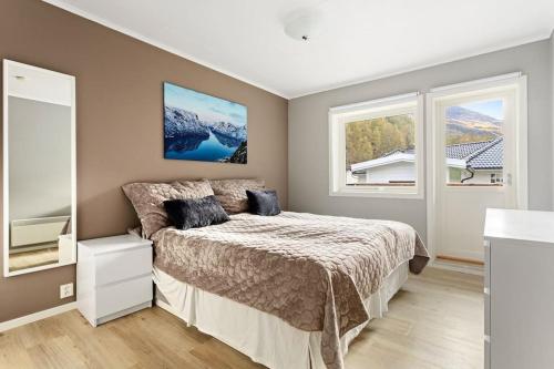 a bedroom with a bed and two windows at Fint hus i Flåm in Aurland
